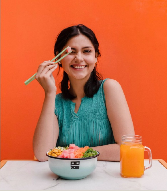 Lifestyle photography — woman with poke bowl on orange backdrop