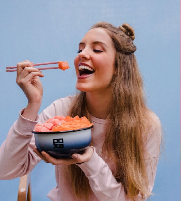 Lifestyle photography — woman eating salmon with chopsticks